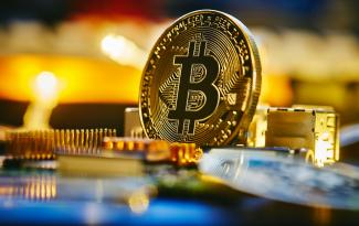 a bitcoin sitting on top of a computer chip by Michael Förtsch courtesy of Unsplash.